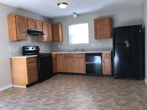 A kitchen with black appliances and wooden cabinets.