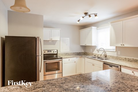 a kitchen with white cabinets and granite counter tops and stainless steel appliances