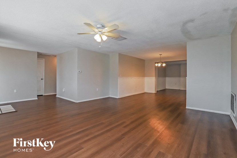 an empty living room with wood floors and a ceiling fan