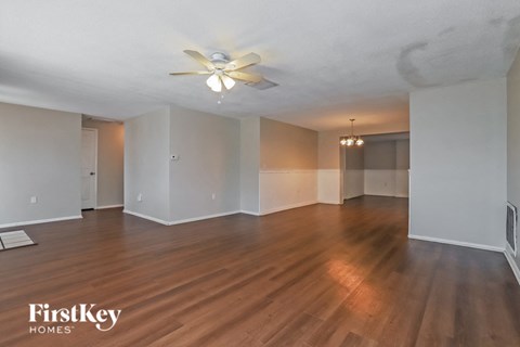 an empty living room with wood floors and a ceiling fan