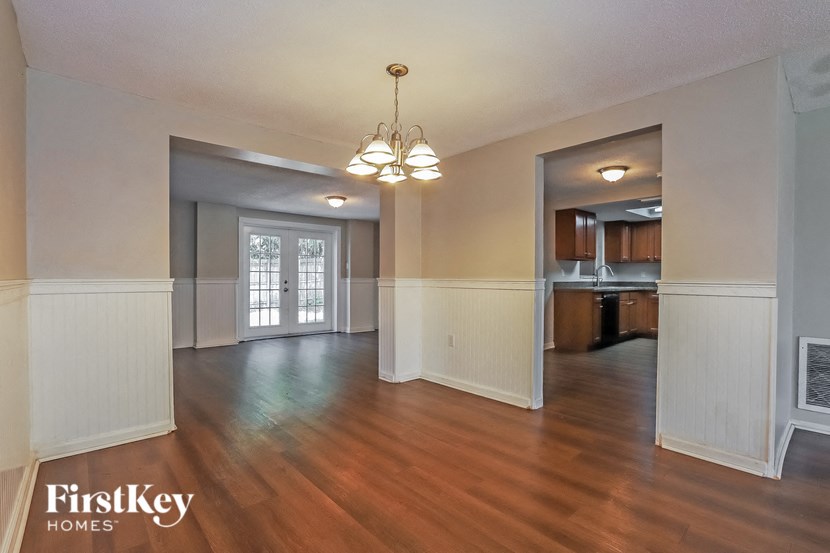 an empty living room and kitchen with wood floors and a chandelier