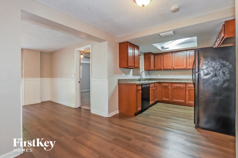 an empty kitchen with wood flooring and a stainless steel refrigerator