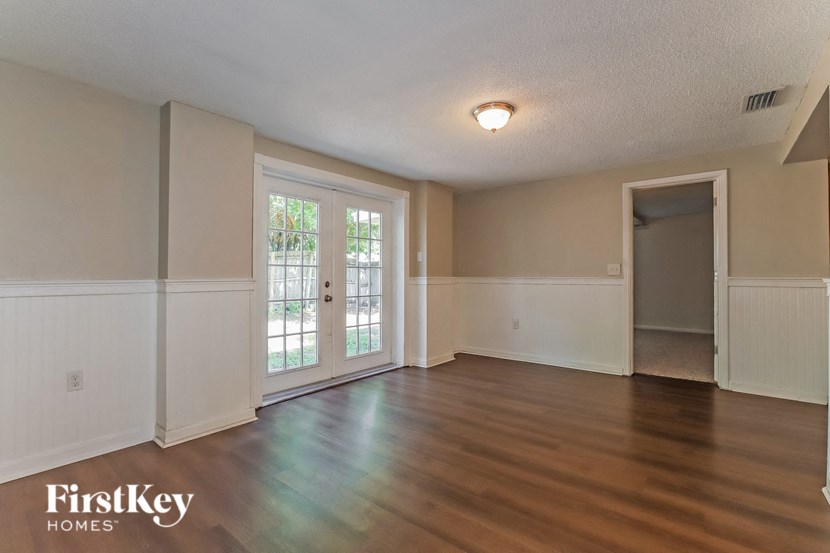 an empty living room with wood floors and a door to a patio