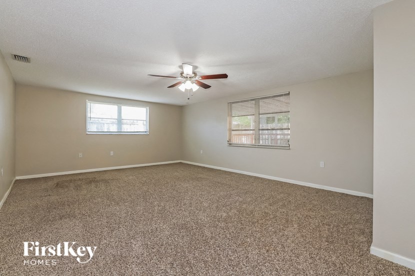 an empty living room with a ceiling fan and a window