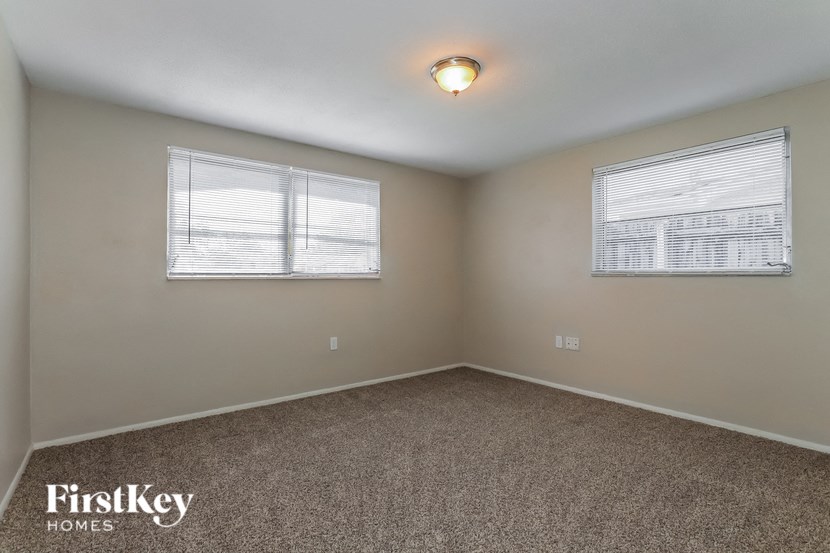a room with carpet and two windows