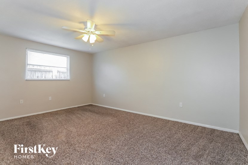 an empty room with a ceiling fan and a window
