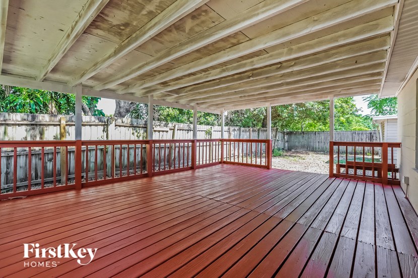 the deck of a house with wood flooring and a bench on it