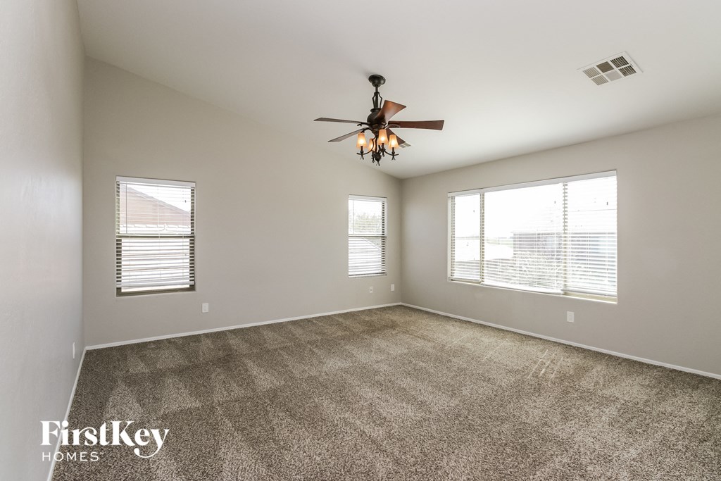 an empty living room with a ceiling fan and two windows