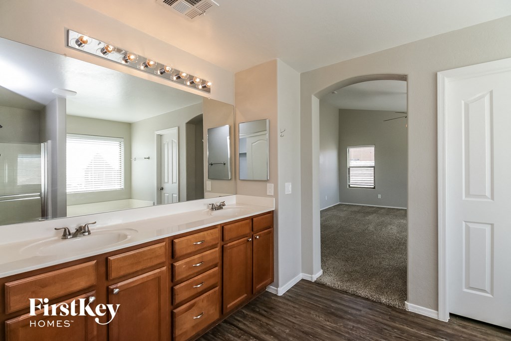 the master bathroom has a large mirror and a large vanity with two sinks