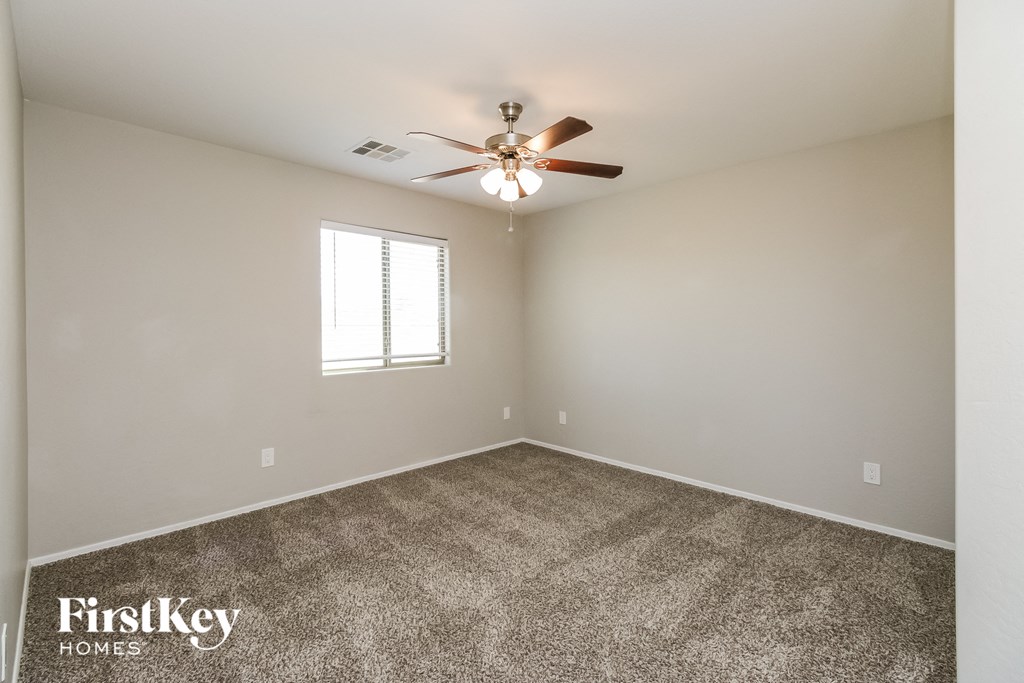 the spacious living room with ceiling fan and carpet