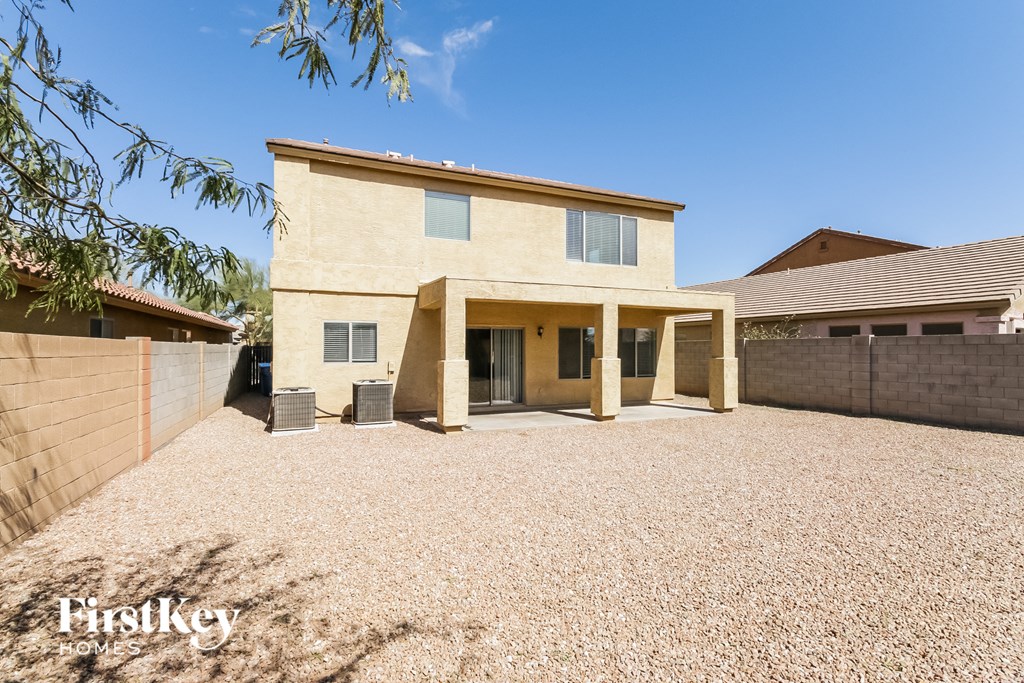 a beige house with a gravel yard and a driveway
