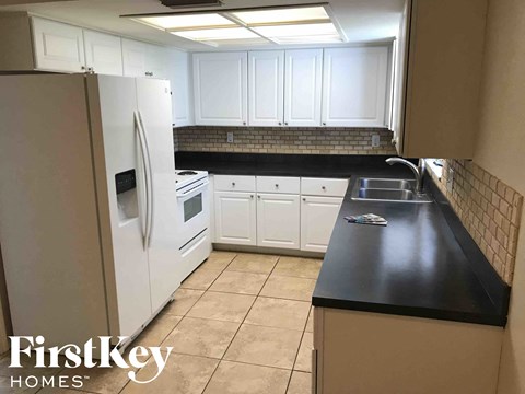 A kitchen with a white fridge and black countertops.