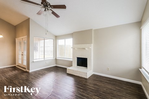 A spacious living room with a fireplace and a ceiling fan.