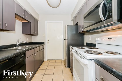 A kitchen with a white door and a black counter top.