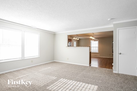 A spacious empty room with a carpet on the floor and a door on the right side.