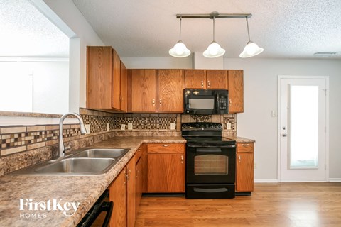A kitchen with wooden cabinets and a black stove top oven.