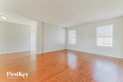 an empty living room with wood floors and white walls