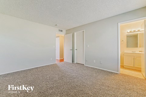 a master bedroom with a carpeted floor and a bathroom