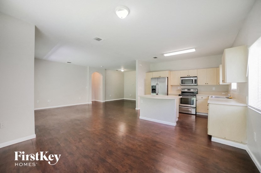 an empty living room and kitchen with wood flooring