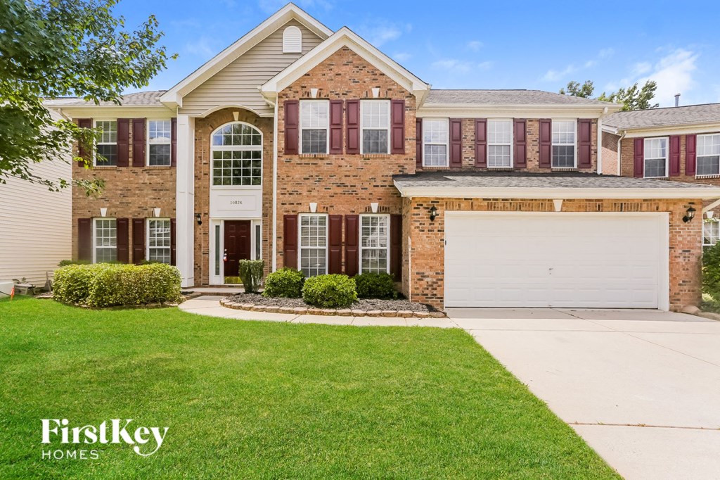 a brick house with a white garage door and a lawn