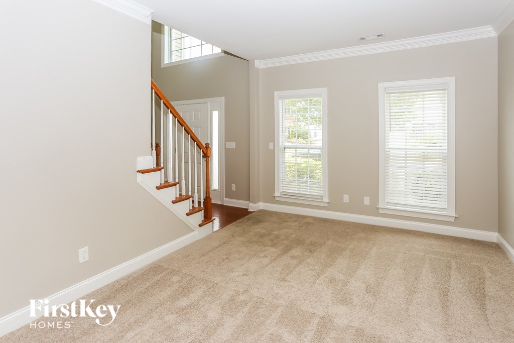 a living room with a staircase and a carpeted floor