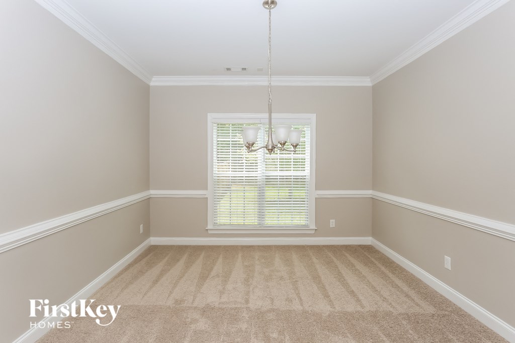 an empty dining room with carpet and a window