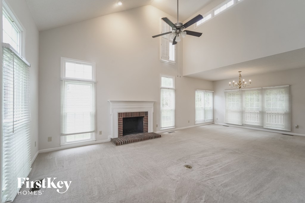 an empty living room with a fireplace and a ceiling fan