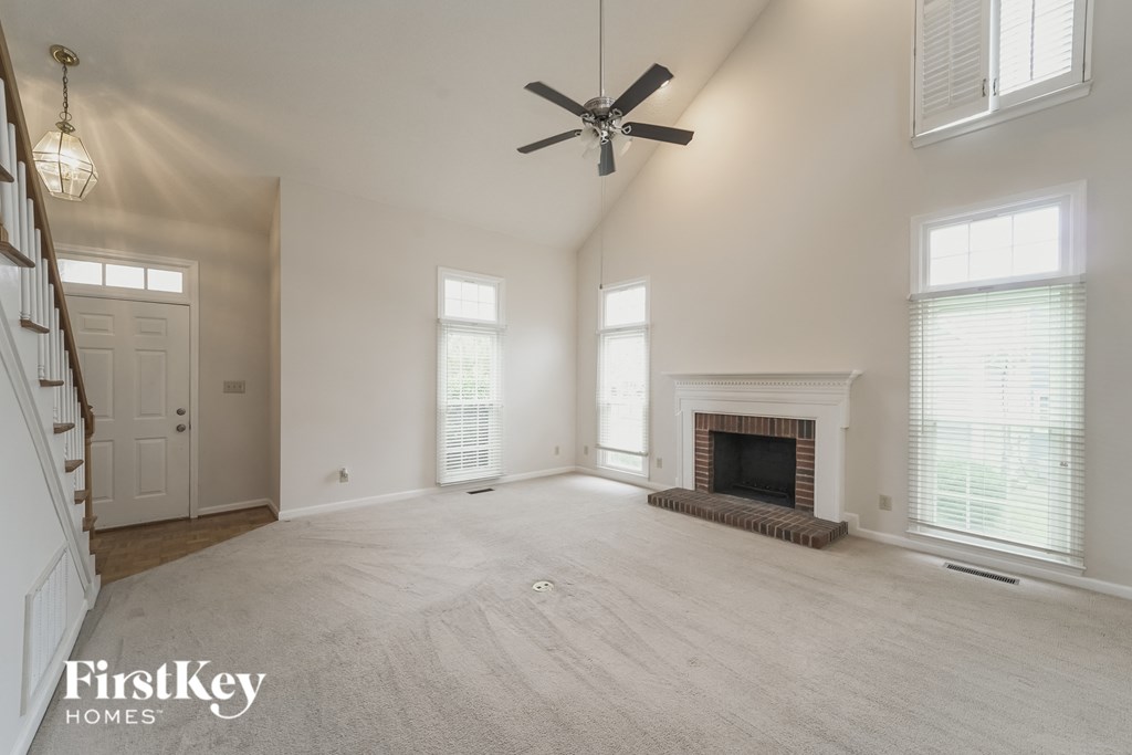 an empty living room with a fireplace and a ceiling fan