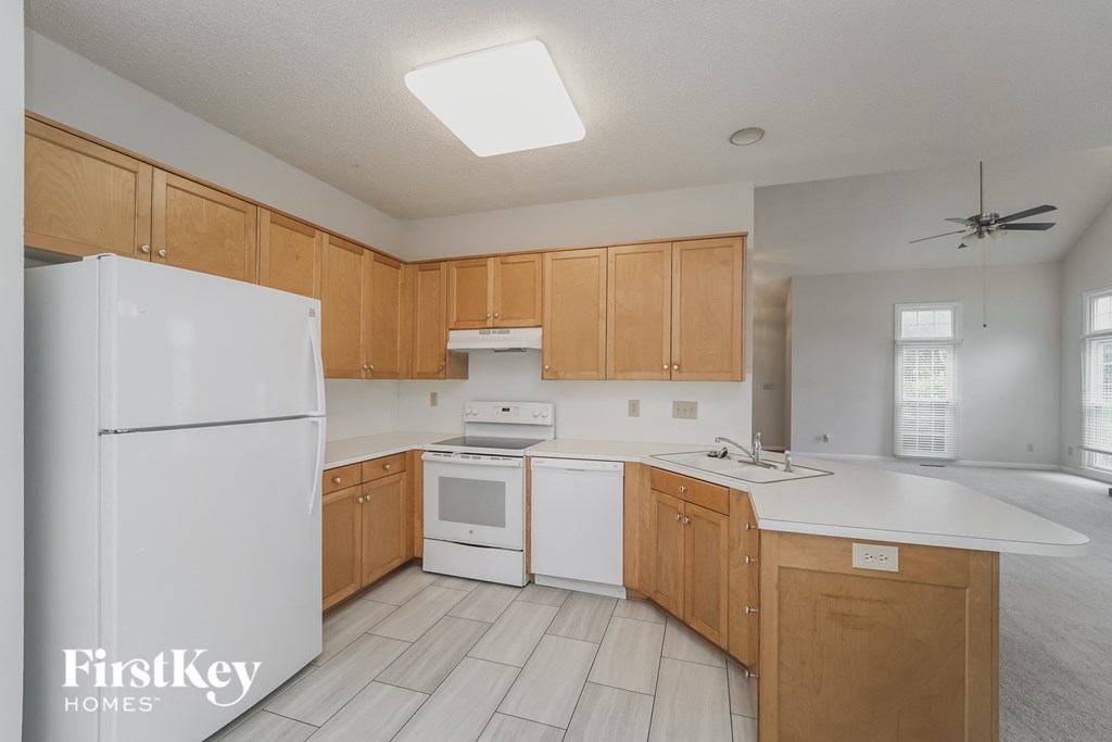 a kitchen with white appliances and wooden cabinets and white counters