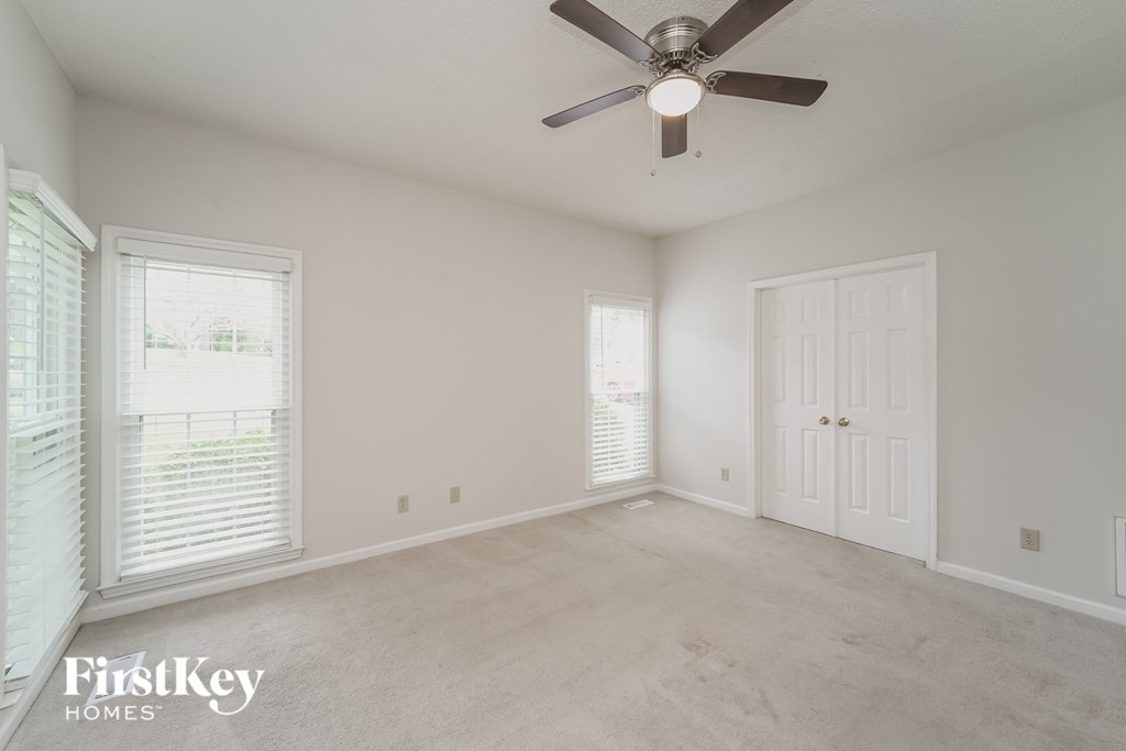 an empty living room with a ceiling fan and a white door