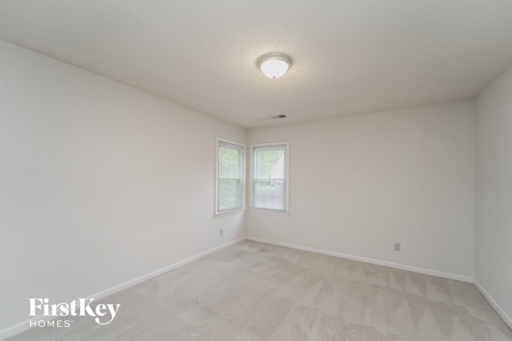 a spacious living room with white walls and a window