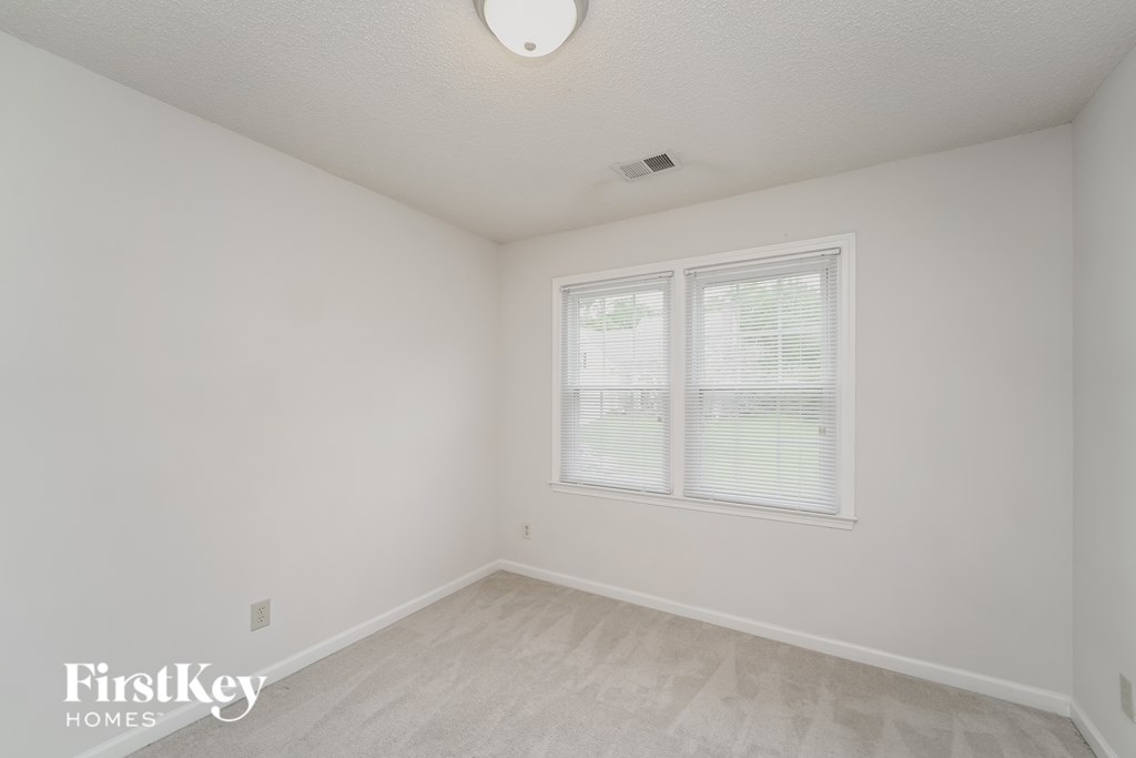 a bedroom with white walls and white carpet and a window