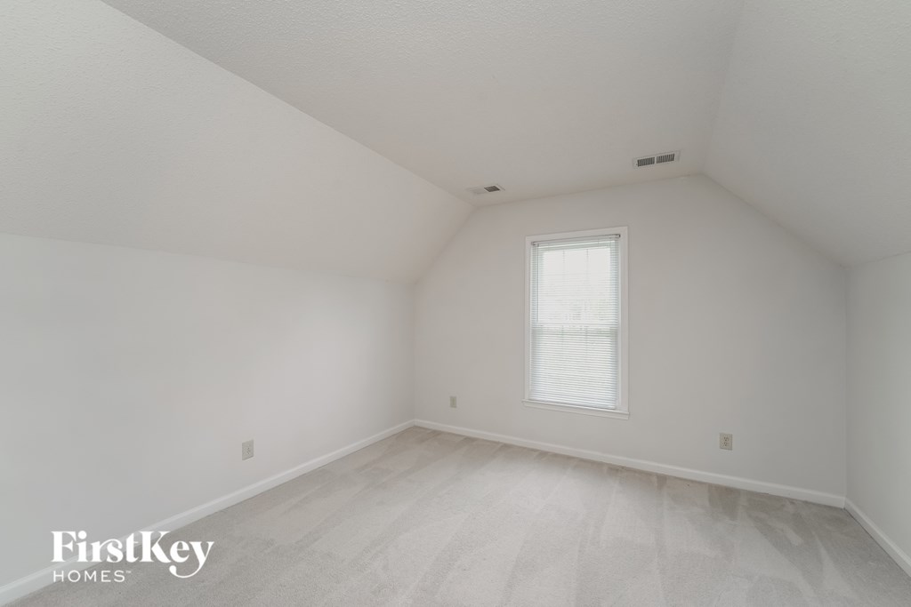 the attic of a home with white walls and a window