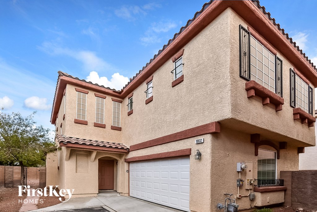 A beige house with a brown roof and a garage door.