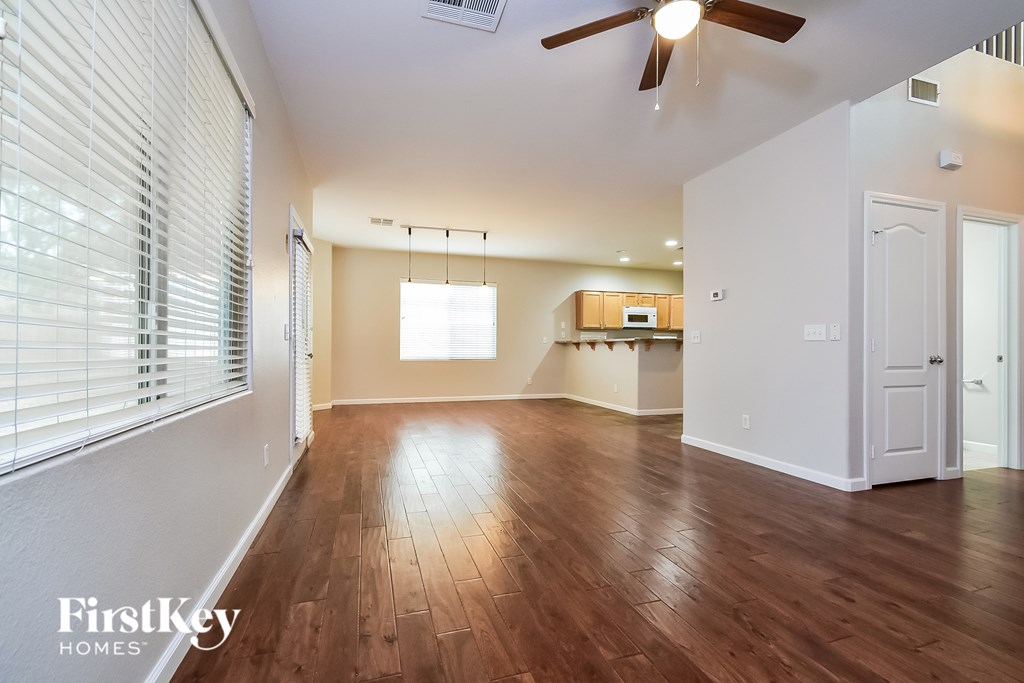 A spacious room with wooden floors and a ceiling fan.