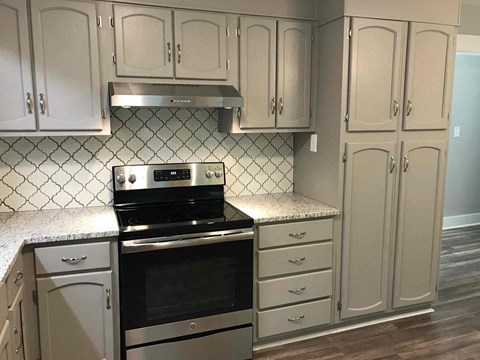 A kitchen with a black stove top oven and white cabinets.
