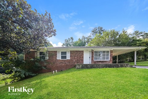 a small brick house with a lawn and a tree