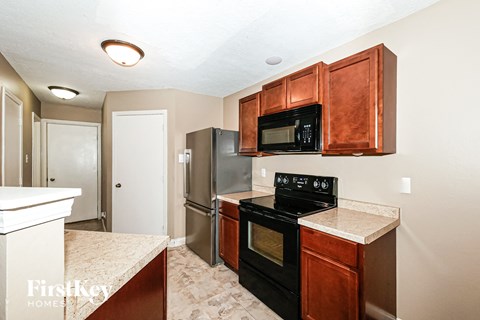 A kitchen with a black stove top oven and microwave above it.
