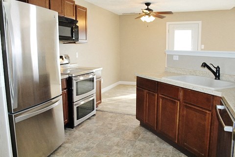 A kitchen with a refrigerator, oven, microwave, and sink.