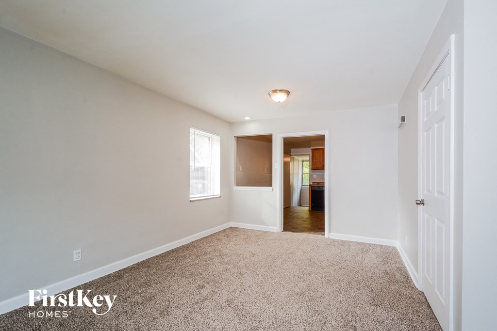 a spacious living room with carpet and a door to a kitchen