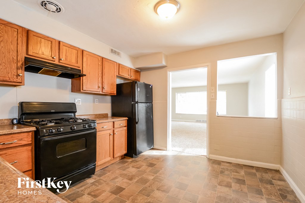 an empty kitchen with black appliances and wooden cabinets