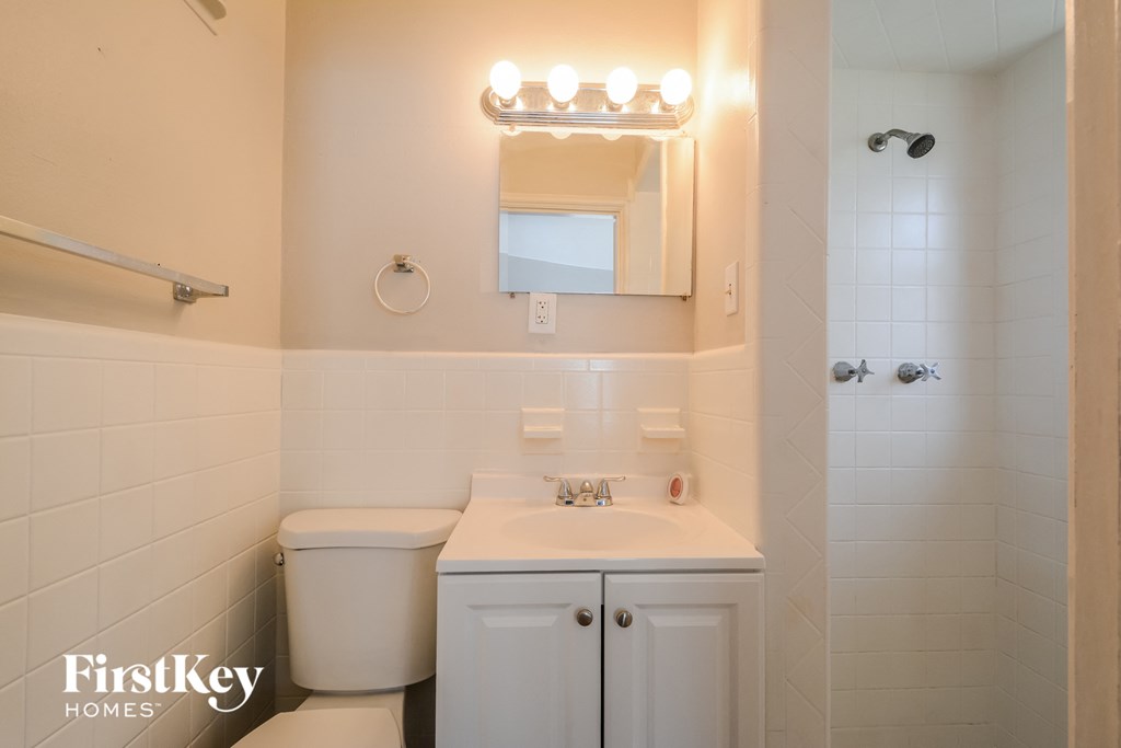 a white bathroom with a sink and a mirror and a toilet