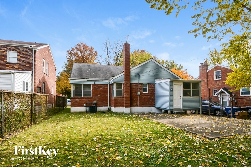 the front of a brick house with a yard and a fence