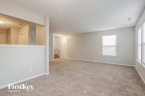 a spacious living room with carpet and a door to the bathroom