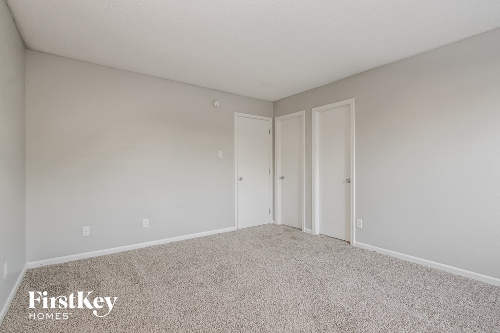 a spacious bedroom with white walls and carpet