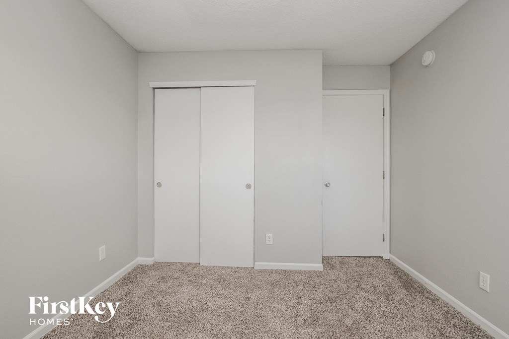 a bedroom with white closets and a carpeted floor