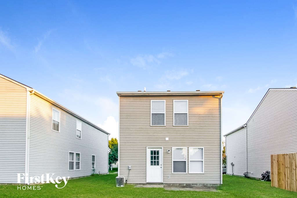 the backyard of a two story house with a blue sky in the background