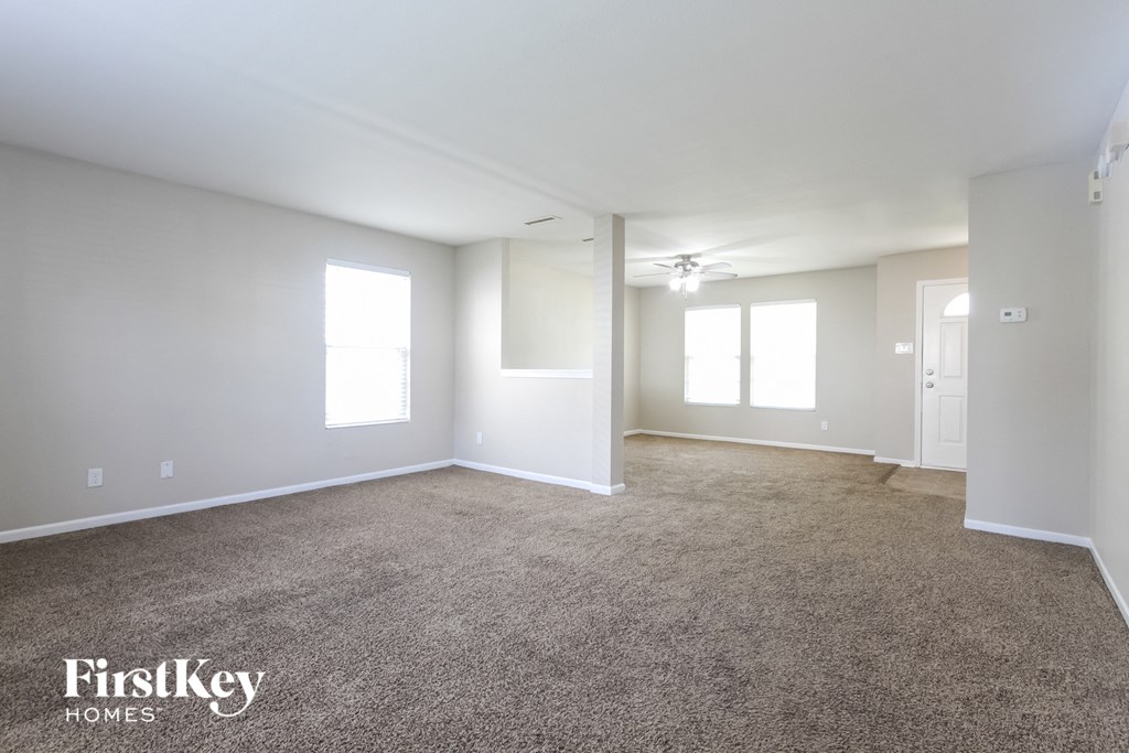 A spacious room with a carpeted floor and a ceiling fan.