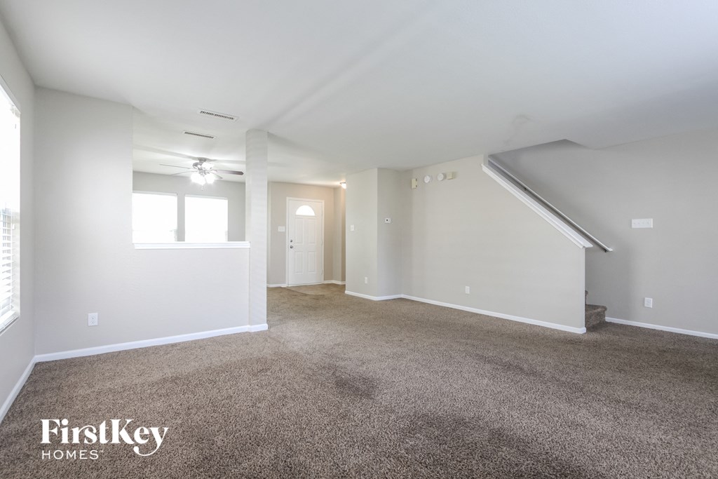 A spacious room with a carpeted floor and a staircase leading to another room.