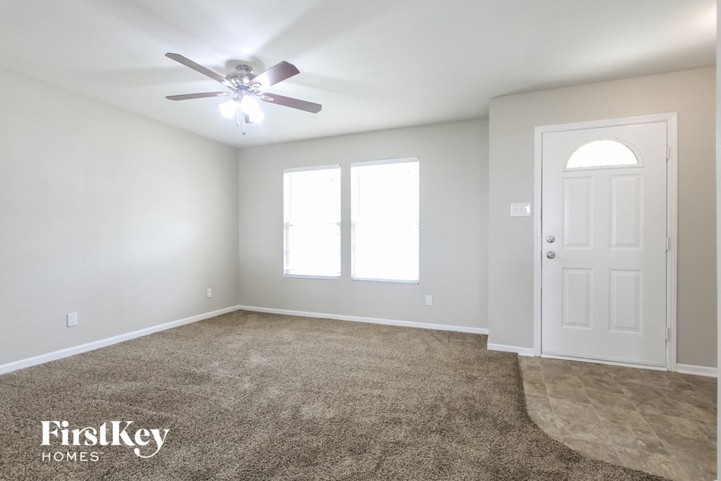 A spacious room with a carpeted floor and a ceiling fan.